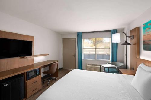 a hotel room with a bed and a desk and a television at La Quinta Inn by Wyndham San Diego - Miramar in Sabre Springs