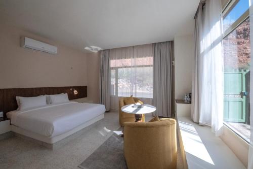 a bedroom with a bed and a table and a window at Wadi Sader in AlUla