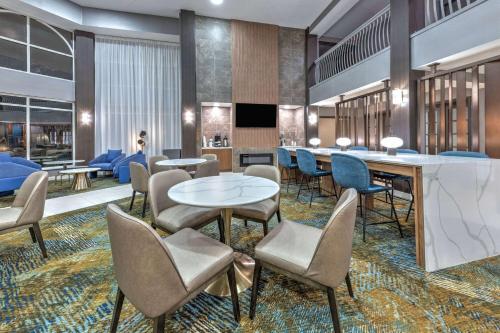 a lobby with tables and chairs and a television at La Quinta by Wyndham Dallas DFW Airport North in Irving