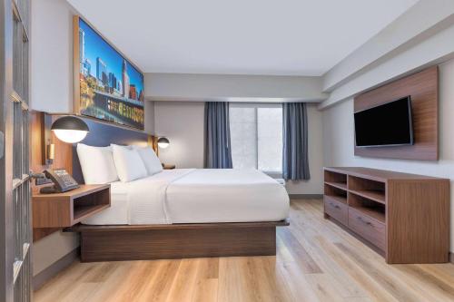 a hotel room with a bed and a television at La Quinta by Wyndham Dallas DFW Airport North in Irving
