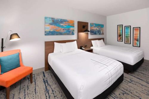 a hotel room with two beds and a chair at La Quinta by Wyndham Rockport - Fulton in Rockport