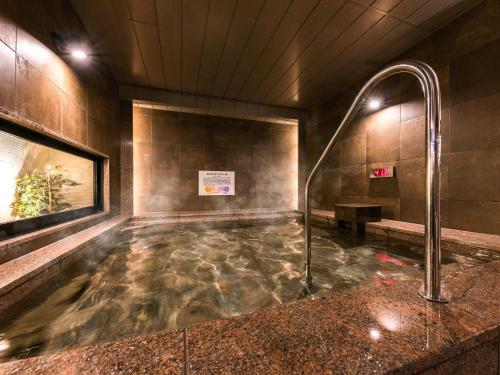 a bath tub with a shower in a building at SUPER HOTEL Ikebukuro West Natural Hot Spring in Tokyo