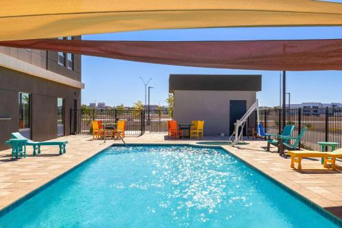 a swimming pool with chairs and tables and a building at La Quinta Inn & Suites by Wyndham Yuma in Yuma
