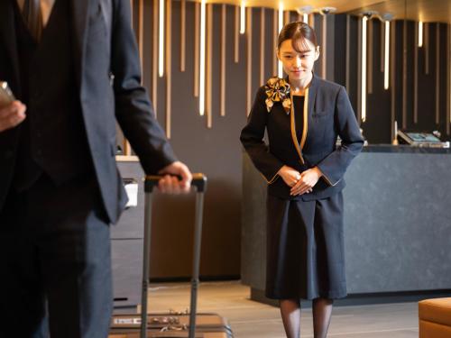 a woman in a suit standing next to a man at SUPER HOTEL Ikebukuro West Natural Hot Spring in Tokyo