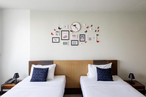 a room with two beds and a clock on the wall at Nature Boutique Hotel Ratchayothin in Bangkok