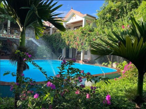 a swimming pool in a garden with flowers at Lucky Homes in Phong Nha