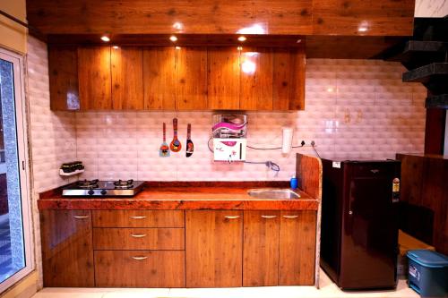 a kitchen with wooden cabinets and a black refrigerator at Malama Stay The Dusk Villa 3BHK Lonavala in Lonavala