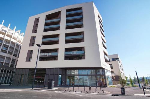 un grand bâtiment blanc dans une rue de la ville dans l'établissement Résidence Bordeaux Rive Droite, à Bordeaux