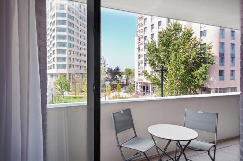 d'un balcon avec deux chaises, une table et une fenêtre. dans l'établissement Résidence Bordeaux Rive Droite, à Bordeaux