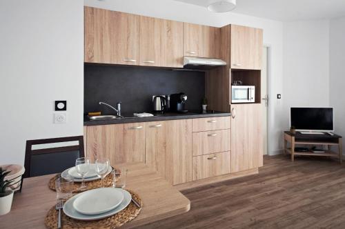 une cuisine avec des placards en bois et une table avec des assiettes. dans l'établissement Résidence Bordeaux Rive Droite, à Bordeaux