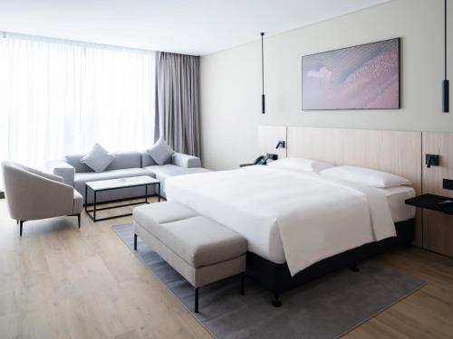 a bedroom with a large white bed and a couch at Park Inn by Radisson Hotel & Apartments Kuwait in Kuwait