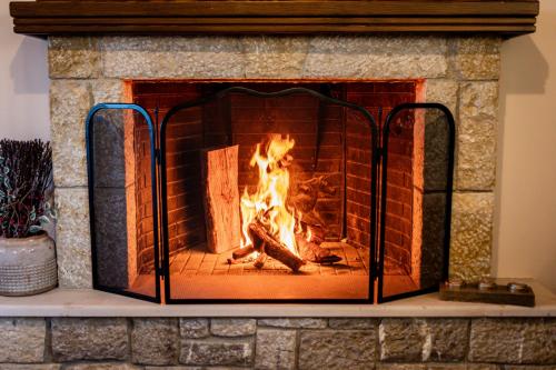 a brick fireplace with a fire in it at Alexi's House in Kalavrita
