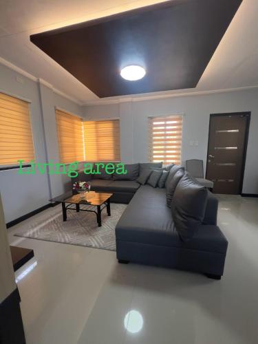 a living room with a black couch and a table at Denelle's fab house staycation in Lucap