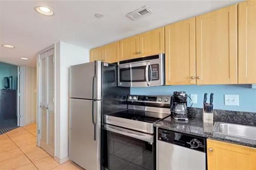 a kitchen with stainless steel appliances and wooden cabinets at Stunning Ocean Front OO Resort 7th Floor 2 Bdr in Myrtle Beach
