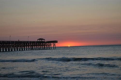 a pier in the ocean with the sun setting at Stunning Ocean Front OO Resort 7th Floor 2 Bdr in Myrtle Beach