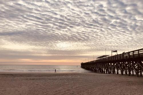 a person walking on the beach near a pier at Stunning Ocean Front OO Resort 7th Floor 2 Bdr in Myrtle Beach