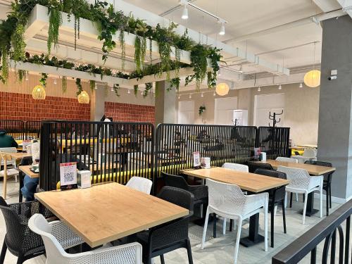 a restaurant with wooden tables and white chairs at Y'estoria апарт-отель, район EXPO центра in Astana