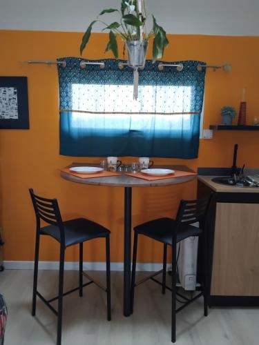 een tafel in een keuken met 2 stoelen en een wastafel bij An ti bihan in Liffré