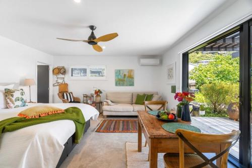 a bedroom with a bed and a table and a couch at Seagrass Studio Guesthouse - By the Beach in Tairua