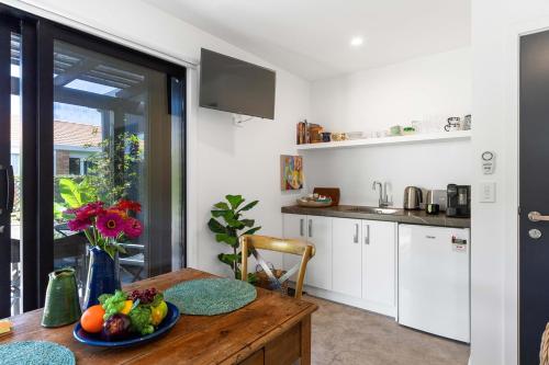 a kitchen with a table with a bowl of fruit on it at Seagrass Studio Guesthouse - By the Beach in Tairua