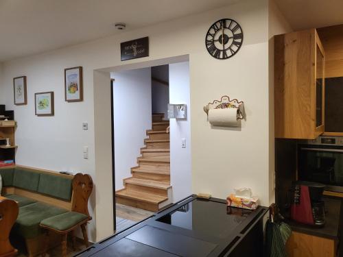 a living room with a staircase and a clock on the wall at Siedls Enzian in Hirschegg Rein
