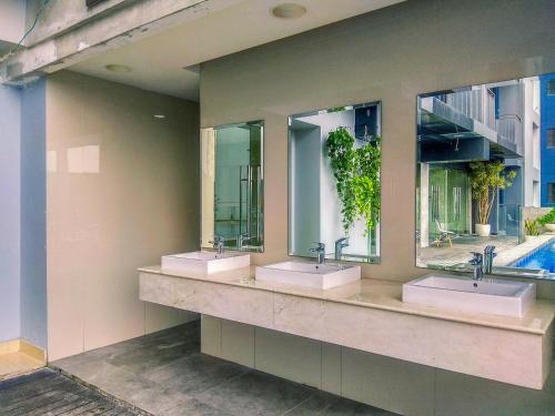 デポックにあるComfort 1BR Apartment at Evenciio Margonda By Travelioの洗面台が3つと鏡が2つあるバスルーム