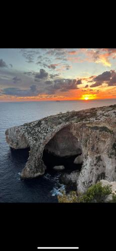 a large rock formation in the ocean with a sunset at Deep Blu Boutique Hotel in Żurrieq