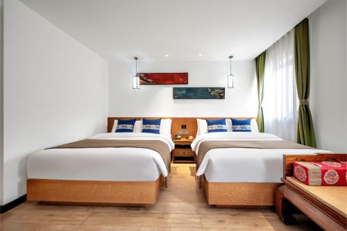 two beds in a room with white walls at Beijing Tangfu Nanluoguxiang Wang Fu Jing Forbidden City Snack Street Hotel,1 stop walking to airport express,3 stop to tiananmen&Free Laundry Dry Service and Free Afternoon Tea &professional Free Tour Ticket Service with English Speaking Staff in Beijing