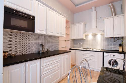 eine weiße Küche mit weißen Schränken und schwarzen Arbeitsplatten in der Unterkunft LEOGRAND Apartments on Doroshenka 34 in Lwiw