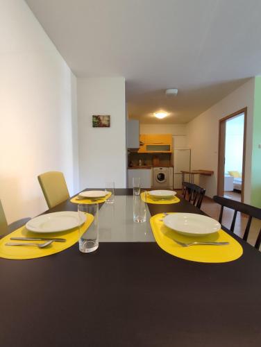 a dining room with yellow chairs and a table with yellow chargers at Veľký štýlový apartmán vo výbornej lokalite in Martin