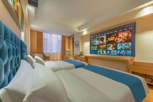 a hotel room with two beds and a large screen at Meihao Mingyue Hotel International Finance City Keyun Road Metro Branch in Guangzhou