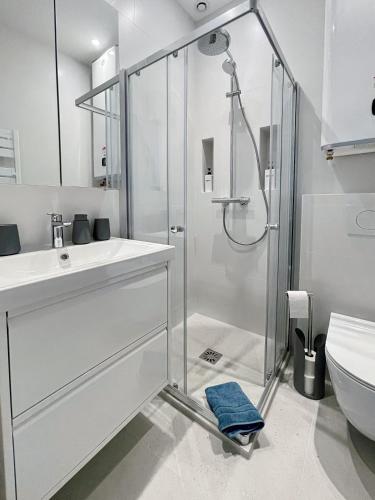 une salle de bain blanche avec une douche et un lavabo dans l'établissement Le Grand Carré Versailles, à Versailles