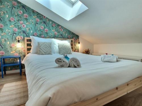 - une chambre avec un grand lit blanc et du papier peint floral dans l'établissement Le Nid des Roses - Hyper Centre, à Albi