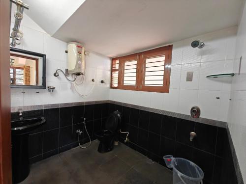 a bathroom with a sink and a toilet and a window at 6bhk Luxury Villa in Mysore
