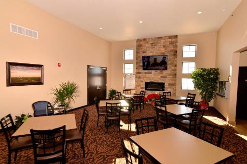 a restaurant with tables and chairs and a fireplace at Cobblestone Inn & Suites - Holstein in Holstein