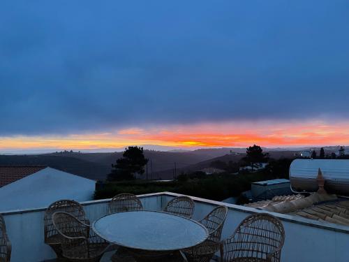 a table and chairs on a balcony with a sunset at AumHome Guesthouse in Aljezur