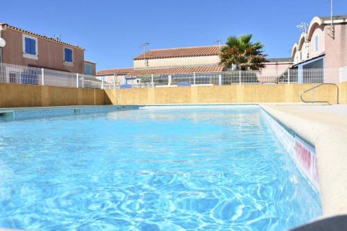 une piscine avec de l'eau bleue dans un immeuble dans l'établissement Maison 3 pièces - Gruissan GA090-056, à Gruissan