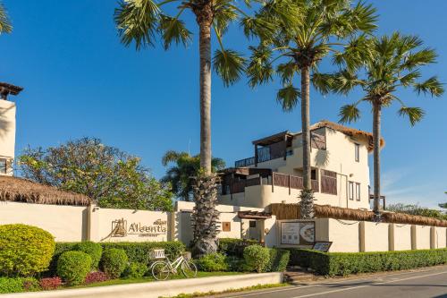 a white building with palm trees in front of a street at Aleenta Hua Hin - Pranburi - The Small Luxury Hotels of the World in Pran Buri