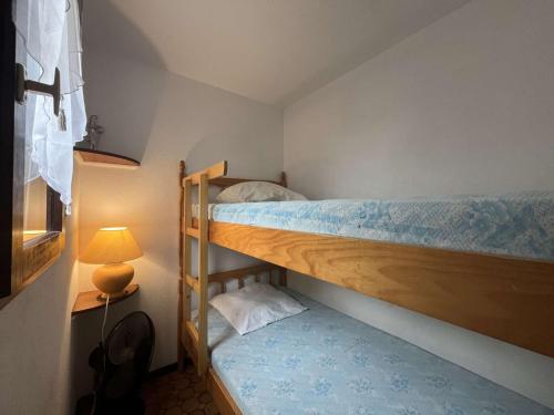 Cette petite chambre comprend 2 lits superposés et une lampe. dans l'établissement Maison 2 pièces cabine - Gruissan GN020-084, à Gruissan