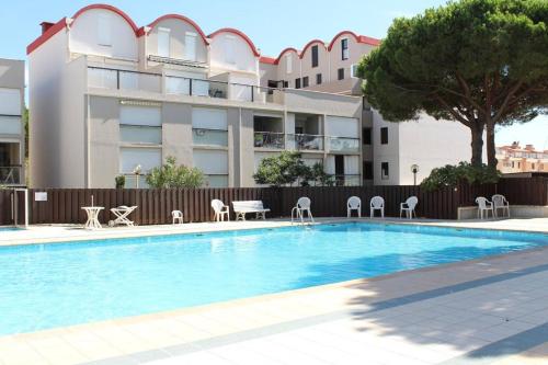 une piscine avec des chaises et un bâtiment dans l'établissement Appartement 3 pièces - Gruissan GN400-028, à Gruissan