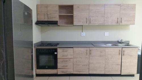 a kitchen with wooden cabinets and a stainless steel refrigerator at BAYSIDE Hotel & Self-catering ISIPINGO in Isipingo