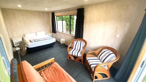 a room with a bed and chairs and a couch at Pataua North By the Beach in Pataua