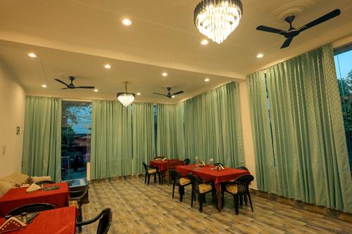 a dining room with red tables and chairs and windows at Falcon guest house in Bharatpur