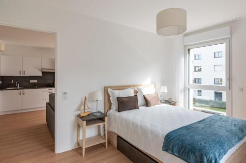 - une chambre blanche avec un grand lit et une cuisine dans l'établissement Résidence Angers, à Angers