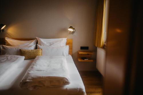 a bedroom with a bed with white sheets and pillows at Hotel Alpin Tyrol - Kitzbüheler Alpen in Sankt Johann in Tirol
