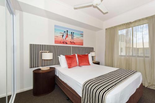 a bedroom with a large bed with red pillows at Metro Advance Apartments & Hotel in Darwin