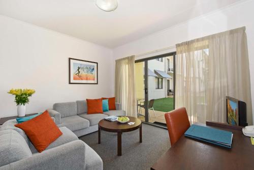 a living room with a couch and a table at Metro Advance Apartments & Hotel in Darwin