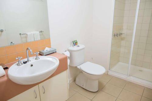 a bathroom with a toilet and a sink and a shower at Metro Advance Apartments & Hotel in Darwin