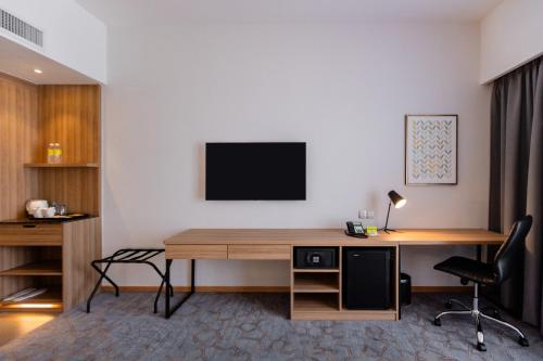 a room with a desk with a television on a wall at Holiday Inn Sepang - Airport in Sepang