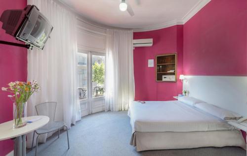 Habitación de color rosa con cama y TV en Crisol Mundial en Buenos Aires